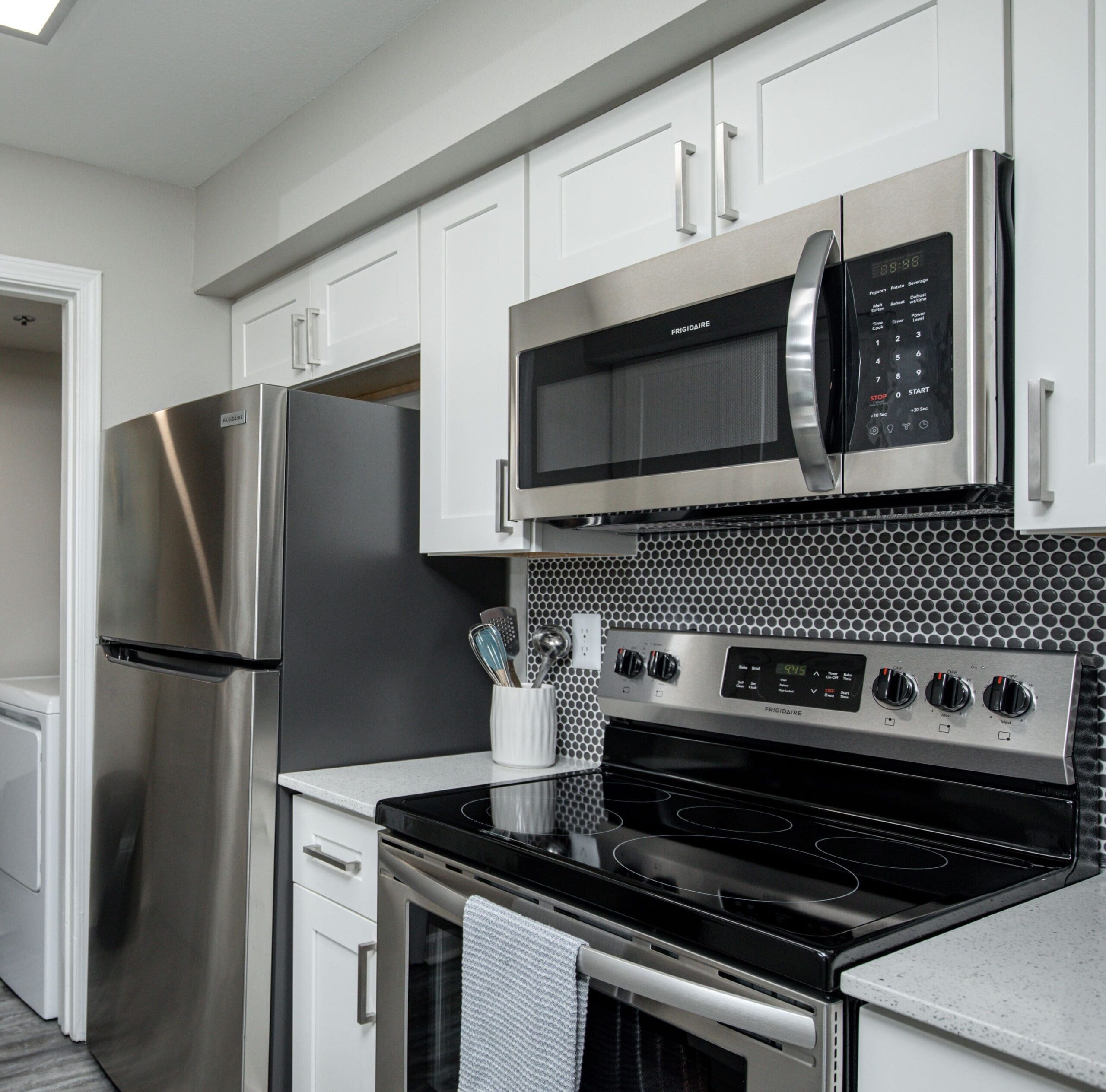 1 BR Apartments in Sandy Springs, GA - The Stratford - Kitchen with Stainless Steel Appliances, Hexagonal Grey Tile Backsplash, and White Cabinetry